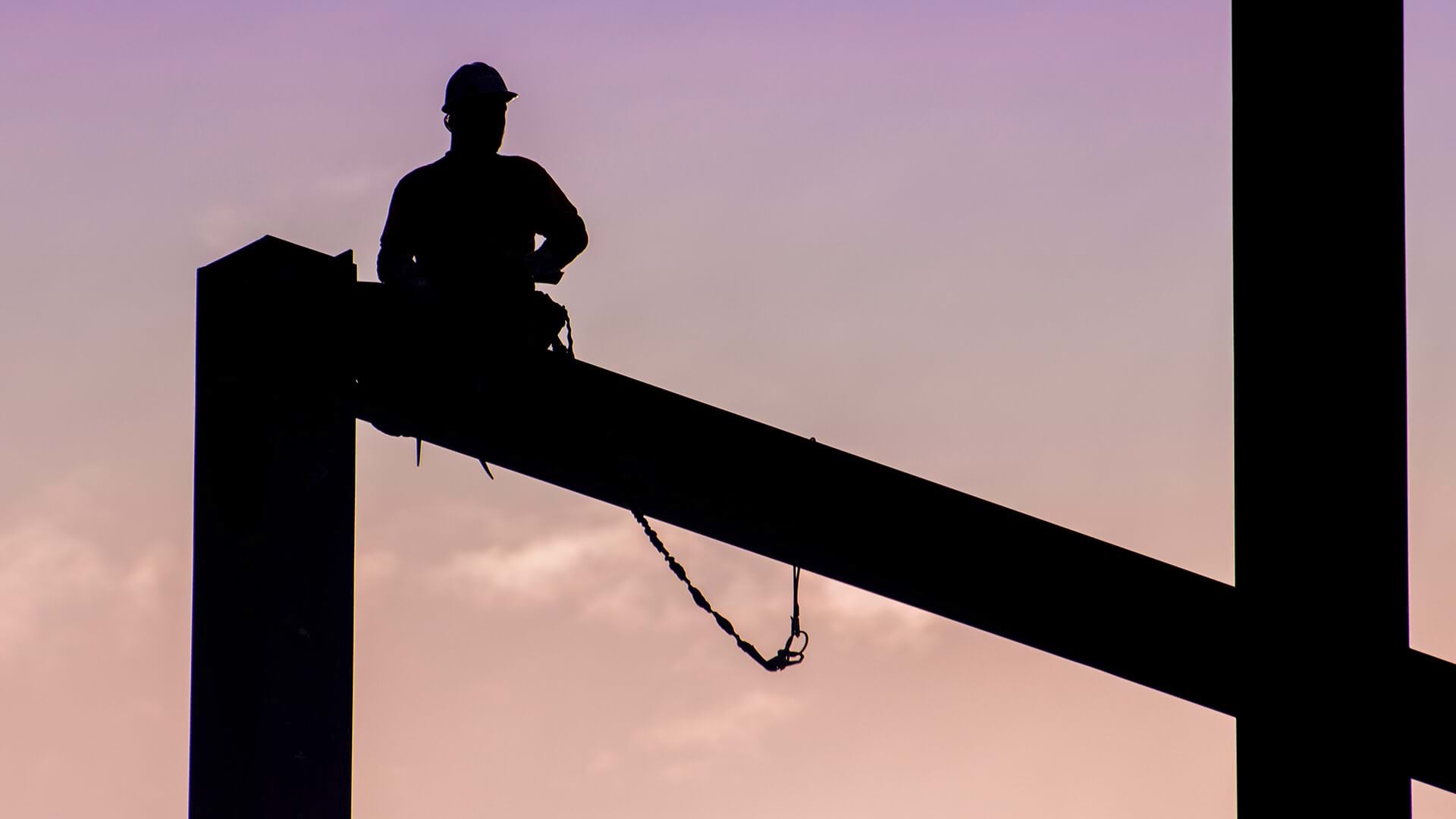 A worker in a high hat, sitting on a beam represents construction firms