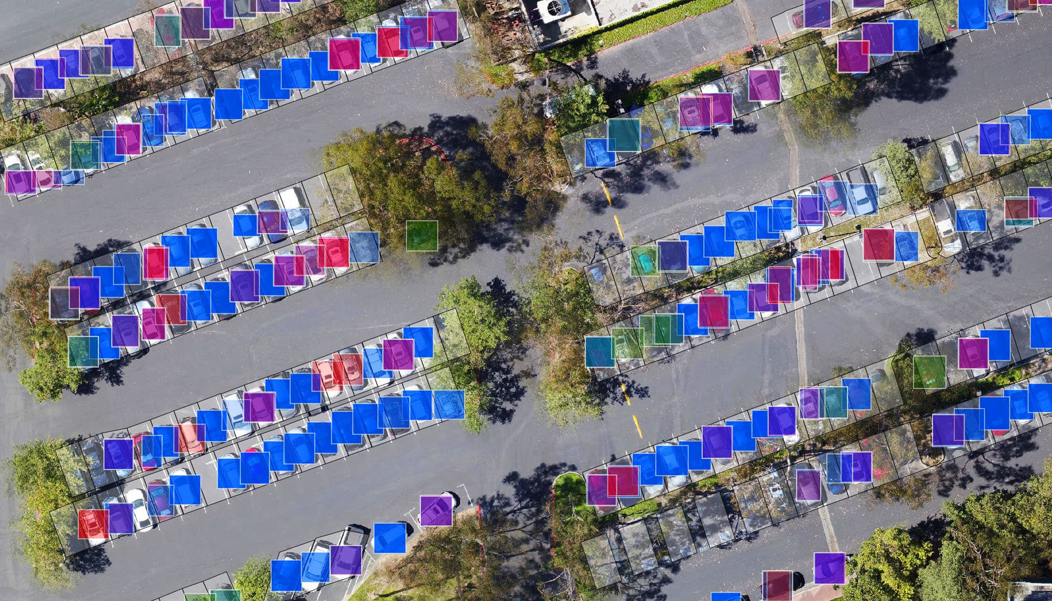 Uma vista aérea de um estacionamento com carros cobertos com quadrados azuis, roxos, verdes e rosa