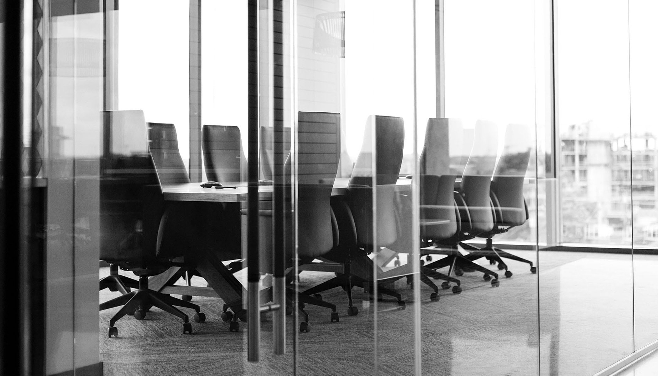 Uma sala de conferências com paredes de vidro, uma grande mesa e cadeiras